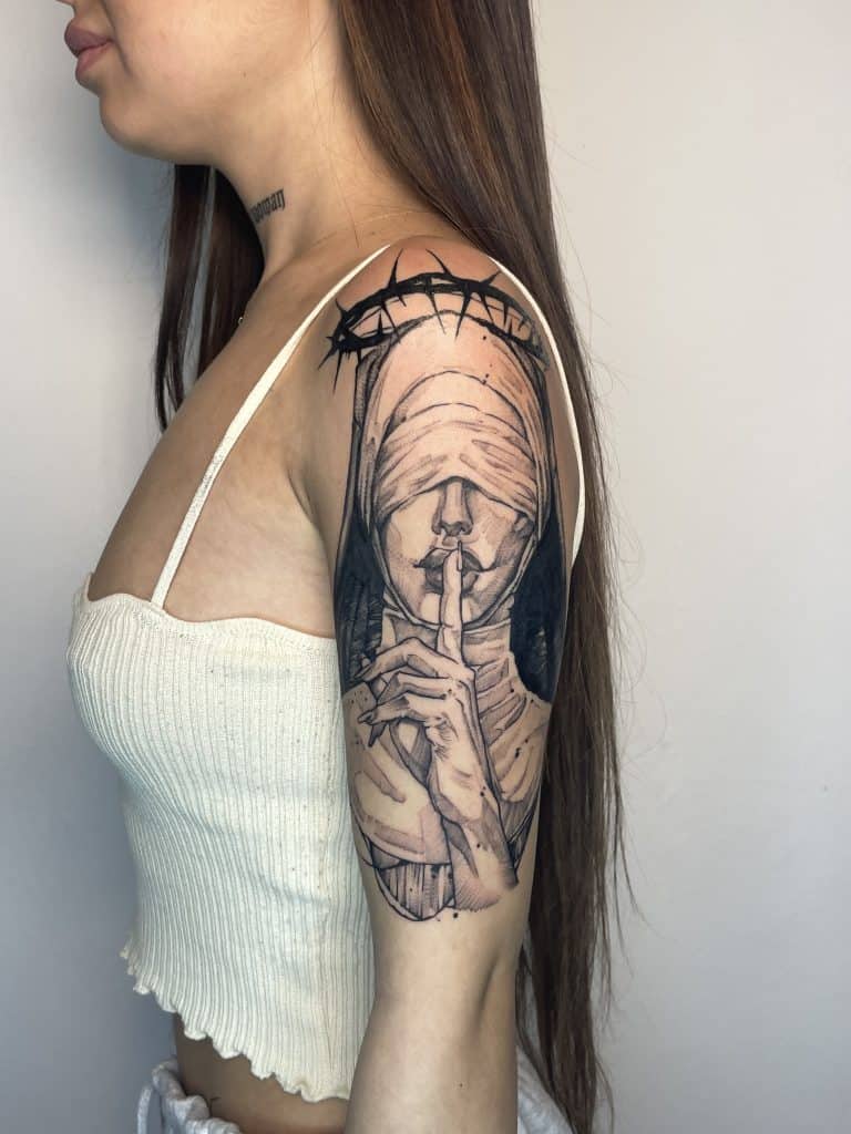 1. tatuaj religios impresionant cu sfântul cu ochii acoperiți și degetul pe buze, realizat în stil blackwork, pe antebraț, la OLD INK TATTOO București.
